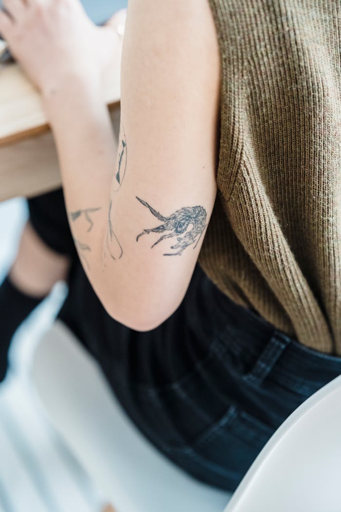 Crafting Captivating Headlines: Your awesome post title goes here Back view of crop faceless tattooed lady in casual clothes sitting on chair near table in light room